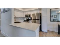 Bright kitchen features stainless steel appliances, white cabinetry, and a stylish backsplash at 718 Nectarine Ct, Henderson, NV 89014