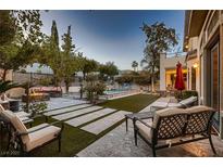 Inviting backyard retreat featuring a sparkling pool, fire pit, and comfortable lounge seating for relaxation at 7501 Midnight Rambler St, Las Vegas, NV 89149