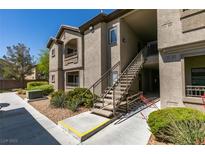 Exterior of a two story condo with an outdoor staircase, greenery and a blue sky in the background at 8250 N Grand Canyon Dr # 2001, Las Vegas, NV 89166