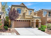 Two-story home featuring a two-car garage, stone accents, balcony, and landscaped front yard at 10230 Danskin Dr, Las Vegas, NV 89166