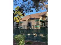 Two story townhouse with green awnings, gated seating area, and mature trees at 520 Elm Dr # 202, Las Vegas, NV 89169