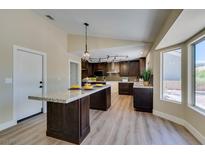 Modern kitchen features an island, wood cabinets, granite countertops, and stainless steel appliances at 9800 Rosamond Dr, Las Vegas, NV 89134
