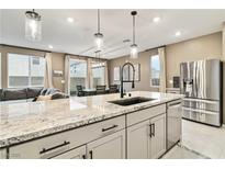 Bright kitchen with granite countertops, pendant lighting, stainless steel appliances, and view into the dining area at 10190 Natural Anchor St, Las Vegas, NV 89166