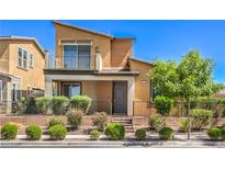 Inviting two-story home featuring desert landscaping, a cozy porch, and an upper-level balcony on a sunny day at 406 Gracious Way, Henderson, NV 89011