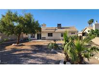 View of the spacious backyard featuring desert landscaping, a mature tree, and a patio area at 4285 El Como Way, Las Vegas, NV 89121