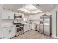 Bright kitchen featuring stainless steel appliances, white cabinetry, and a stylish light fixture at 4745 Madrigal Way, Las Vegas, NV 89122