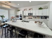 Bright kitchen features white cabinets, stainless appliances, and a large island with seating at 5422 Nestled Moon Ct, Las Vegas, NV 89131