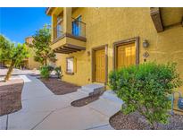 Inviting townhouse exterior with a cozy balcony, well-maintained landscape, and pathway leading to the entrance at 5915 Nuevo Leon St # 8, North Las Vegas, NV 89031