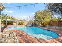 Beautiful pool with rock waterfall feature, lush landscaping, and spa for outdoor relaxation at 6907 May Basket Ave, Las Vegas, NV 89131