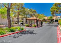 View of the community entrance gate with mature trees and manicured landscaping offering security and curb appeal at 2451 N Rainbow Blvd # 1066, Las Vegas, NV 89108