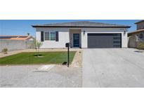 Charming single-story home featuring desert landscaping and a modern garage door at 3440 Ernest St, North Las Vegas, NV 89032