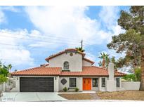 Charming two-story home with a terra cotta tile roof, and an inviting entrance featuring vibrant orange doors at 5757 Charles Holden Ct, Las Vegas, NV 89103