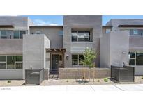 Modern townhouse featuring gray stucco, large windows, and a small landscaped front yard at 1467 Melodic Lark Ln, Las Vegas, NV 89138