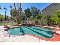 Inviting backyard pool features a rock waterfall, lush landscaping, and a brick-lined edge at 3633 Fox Heather Dr, Las Vegas, NV 89129