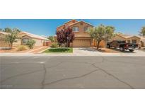 Two-story home featuring a manicured lawn, desert landscaping, and a neutral-toned exterior at 7690 Morning Lake Dr, Las Vegas, NV 89131