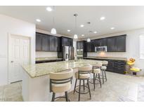 A spacious kitchen features dark cabinetry, granite countertops, and a large island with seating at 10742 Cowlite Ave, Las Vegas, NV 89166