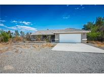 Charming single-story home with a two-car garage and a desert landscape, bathed in bright sunlight at 1351 Fawn St, Pahrump, NV 89048