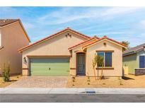 Charming single-story home featuring a green garage door, low maintenance landscaping, and a brick driveway at 3232 Lahontan St, North Las Vegas, NV 89032