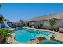 Backyard pool features rock details, water slide, and lush landscaping for a private outdoor oasis at 3832 Alder Creek Ct, North Las Vegas, NV 89032