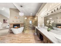 Beautiful bathroom with a fireplace, chandelier, soaking tub, large mirrors, and walk-in shower at 8100 Lake Hills Dr, Las Vegas, NV 89128