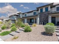 Modern townhome with stone accents, desert landscaping, and a paved walkway leading to the front door at 835 Jigglypuff Pl, Henderson, NV 89011