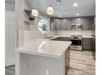 Modern kitchen features quartz countertops, stainless steel appliances, gray cabinets, and stylish pendant lighting at 5018 S Rainbow Blvd # 202, Las Vegas, NV 89118