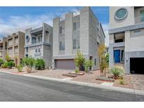 Modern townhomes feature desert landscaping, brick-paved driveways, and gray concrete exteriors under a partly cloudy sky at 8056 Haywood Estate Ave, Las Vegas, NV 89113