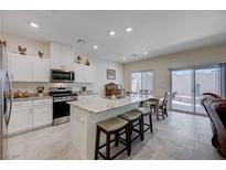 Bright kitchen boasts stainless steel appliances, granite counters, and center island with bar stool seating at 387 Larksong Ave, Henderson, NV 89011