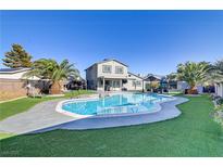 Inviting backyard with a large pool, lush green lawn, mature trees, and covered patio, perfect for outdoor entertaining at 4474 Dawley Ct, Las Vegas, NV 89104