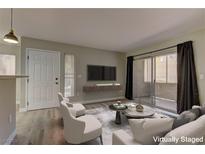 Bright living room with wood floors, neutral tones, a sliding glass door to the balcony, and contemporary furnishings at 5710 E Tropicana Ave # 1216, Las Vegas, NV 89122