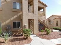 Tan two-story condo building with front entry, landscape and stairs to the second level at 2110 Los Feliz St # 1083, Las Vegas, NV 89156