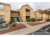 A tan condo building features a sidewalk, landscaped yard and reserved parking at 2300 E Silverado Ranch Blvd # 1070, Las Vegas, NV 89183