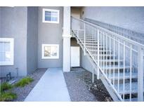 Modern condo exterior with gray stucco, white trim, and staircase leading to upper units at 6160 Rumrill St # 121, Las Vegas, NV 89113