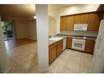 Well-lit kitchen with wooden cabinets, granite countertops, and tile flooring at 62 E Serene Ave # 129, Las Vegas, NV 89123