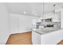 A beautifully renovated kitchen featuring white cabinets, stainless steel appliances, and granite countertops with modern hanging lights at 1121 W Monroe Ave, Las Vegas, NV 89106