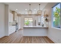 Bright kitchen features modern appliances, pendant lighting, white cabinets, and a counter with a bar overhang at 1506 Camino Summit Ave, Henderson, NV 89012