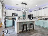 Bright kitchen with white and aqua cabinets, marble countertops, and a stylish island with pendant lighting at 1604 Patrick Thomas Ct, North Las Vegas, NV 89086