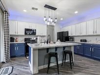 Modern kitchen with blue and white cabinets, stylish lighting fixture, and marble countertops at 1604 Patrick Thomas Ct, North Las Vegas, NV 89086