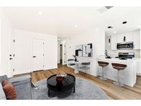 Bright living room with a modern kitchen featuring white cabinets, an island with marble countertops, and stainless steel appliances at 5078 Mountain Vista St, Las Vegas, NV 89120