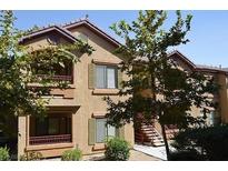 Two-story tan condo complex with greenery and stairs leading to the units at 8250 N Grand Canyon Dr # 2154, Las Vegas, NV 89166