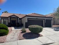Charming single-story home featuring desert landscaping, a tile roof, and a spacious three-car garage at 8847 W Katie Ave, Las Vegas, NV 89147