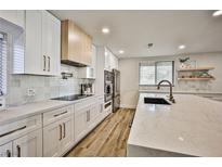 Modern kitchen featuring white cabinets, quartz countertops, stainless steel appliances, and a stylish island with seating at 9340 W Washburn Rd, Las Vegas, NV 89149