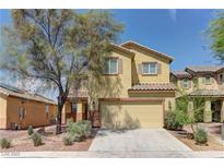 Charming two-story home showcasing a tan facade, complemented by a two car garage, desert landscaping, and shade tree at 952 Crescent Falls St, Henderson, NV 89011