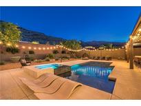 Inviting backyard features a sparkling pool, spa, lounge chairs and string lights for evening enjoyment at 10149 Terrastone Dr, Las Vegas, NV 89148