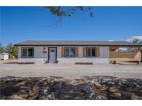 Charming single-story home with white siding, black trim, wood accents, and desert landscaping at 1050 Bruce St, Pahrump, NV 89048