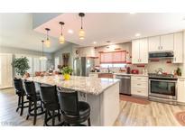 Bright kitchen boasts a large island with granite countertops, pendant lighting, and stainless steel appliances at 8516 Millsboro Dr, Las Vegas, NV 89134