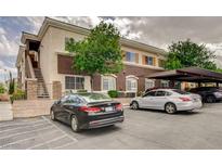 View of the condo building with covered parking and a lush green tree in front at 9303 Gilcrease Ave # 2198, Las Vegas, NV 89149