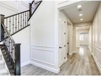 Bright hallway with wood floors, paneled walls, and a staircase with dark wood banister at 10164 Phelps Lake Ct, Las Vegas, NV 89148