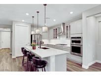 This kitchen features a large island with seating, stainless steel appliances and modern pendant lighting at 2386 Millergrove Ave, North Las Vegas, NV 89086