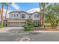 Two-story stucco home featuring a three-car garage, tile roof, and professionally landscaped yard with palm trees at 253 White Willow Ave, Las Vegas, NV 89123